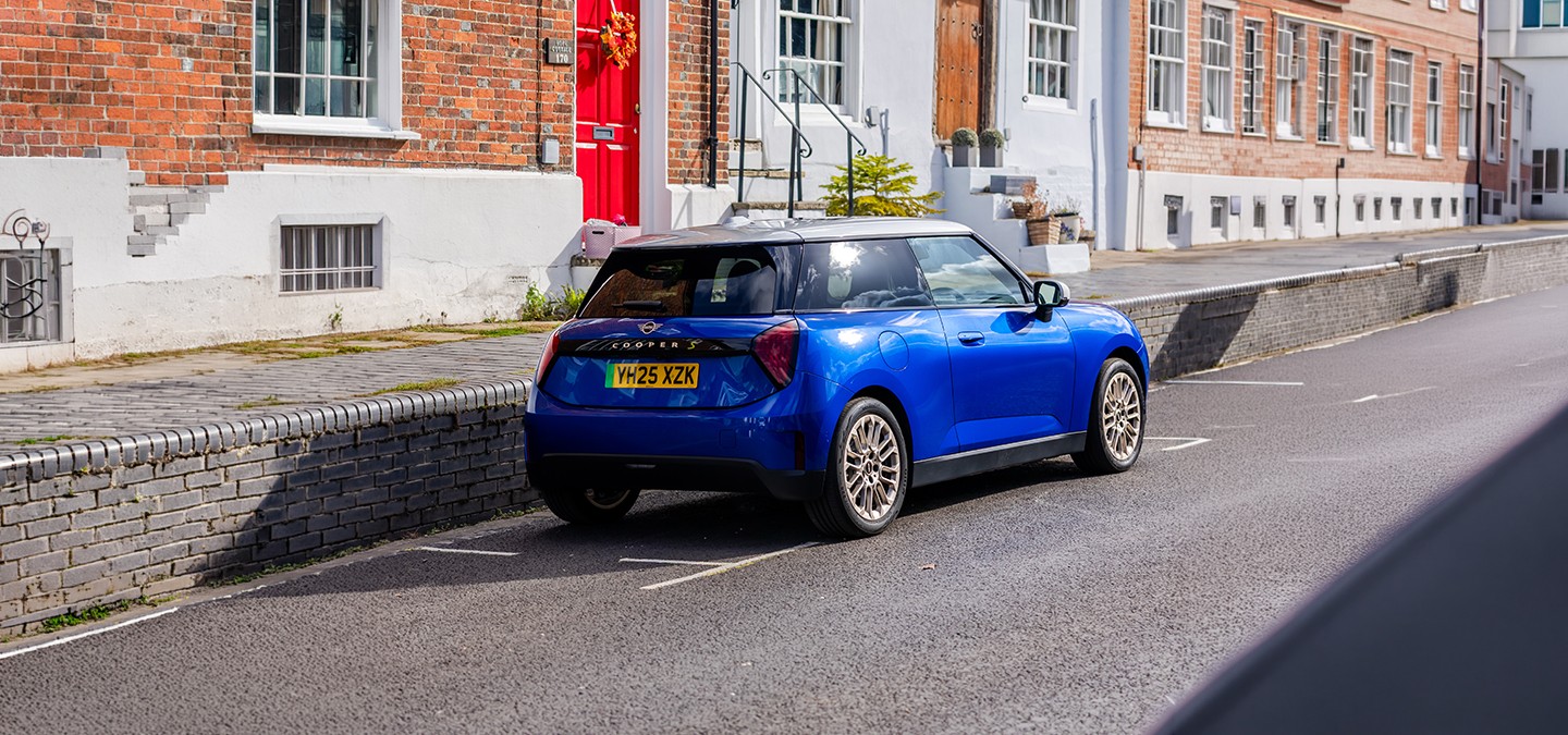 Rear view of the MINI Cooper in Sunnyside Yellow with Black Roof parking.